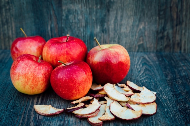 Des pommes séchées et des roseaux reposent sur une table en bois sombre.