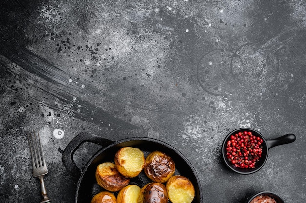 Pommes de terre au four avec ensemble de romarin, dans une poêle en fonte à frire, sur fond de table en pierre noire noire, vue de dessus à plat, avec espace de copie pour le texte
