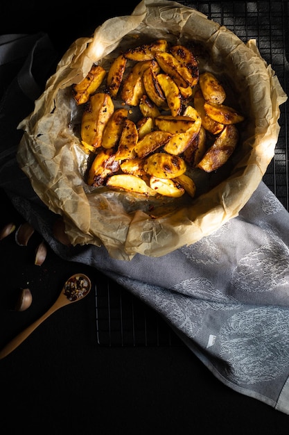 Pommes de terre au four avec épices et ail sur fond sombre dans un moule en métal