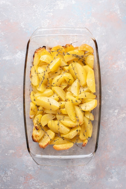 Pommes de terre au four avec de l'huile d'olive, de l'ail et du thym sous forme de verre. Mise à plat, vue de dessus.
