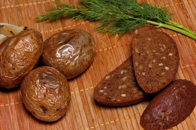 Pommes de terre au four et pain noir sur fond en bois. Nourriture villageoise