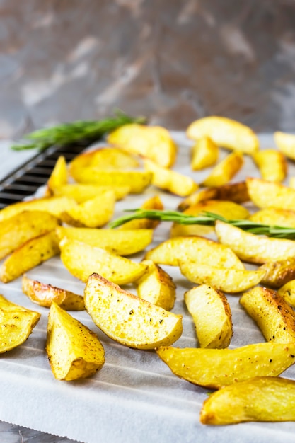 Pommes de terre au four sur une plaque à pâtisserie avec des morceaux d&#39;épices et de romarin