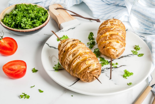 Pommes de terre au fromage tornade au persil et tomates, sur fond de marbre blanc, espace copie