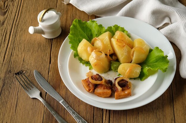 Pommes de terre bouillies avec des crépitements de la nourriture et de la cuisine maison sur une table en bois ustensiles blancs