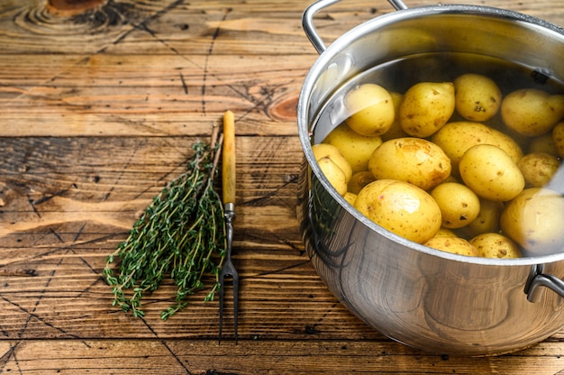 Pommes de terre bouillies dans une casserole. Fond en bois. Vue de dessus. Copiez l'espace.