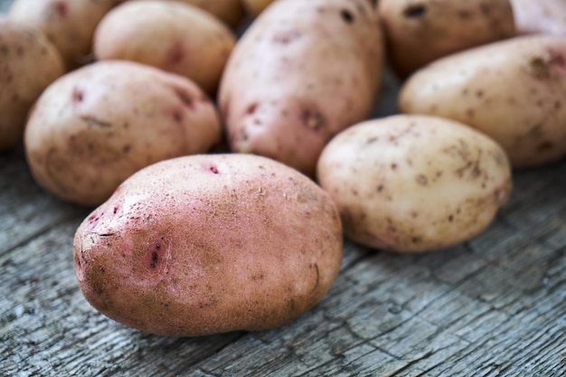 Photo pommes de terre crues non pelées posées sur les planches de bois brutes