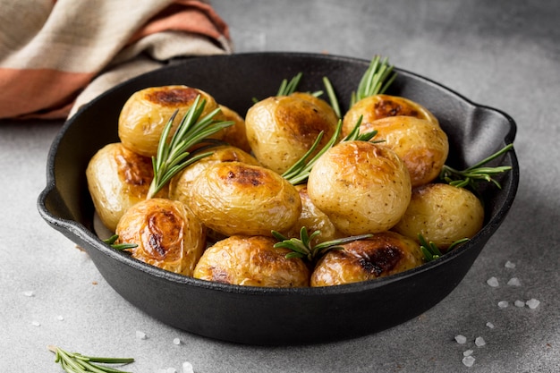 Pommes de terre entières frites (cuites au four) avec du romarin et du sel dans une poêle à frire, croûte vermeille, aliments appétissants