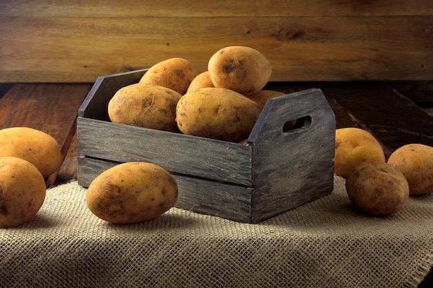 Pommes de terre fraîches et crues récoltées dans les plantations et placées dans une boîte rustique sur une table en bois.