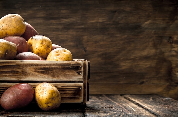 Photo pommes de terre fraîches dans une boîte en bois. sur un fond en bois.