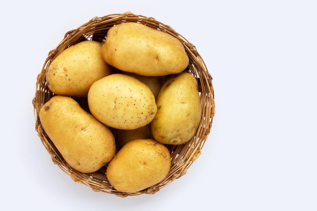 Pommes de terre fraîches dans un panier en bambou sur fond blanc.