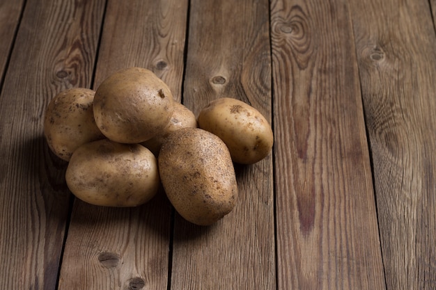 Photo pommes de terre fraîches sur table en bois naturel. nourriture laide à la mode