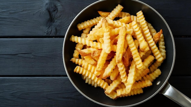 Photo des pommes de terre frites frites dans une casserole à fond en bois noir vue supérieure