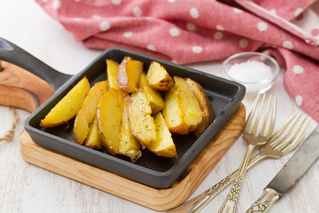 Pommes de terre frites sur une poêle noire sur une table blanche