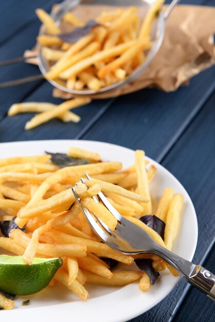 Pommes de terre frites avec sauce et citron vert sur plateau blanc