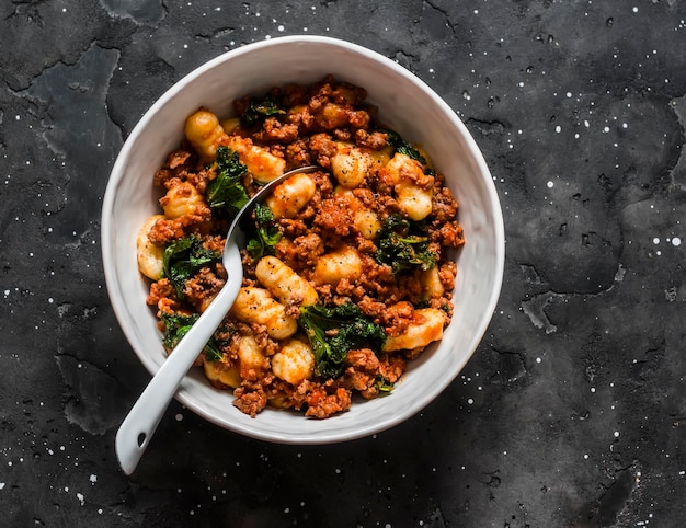 Pommes de terre gnocchi avec sauce bolognaise à la dinde et chou frisé sur fond sombre vue de dessus