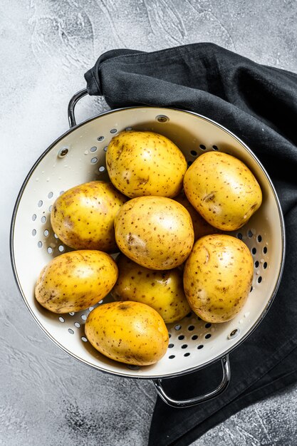 Pommes de terre lavées crues dans une passoire