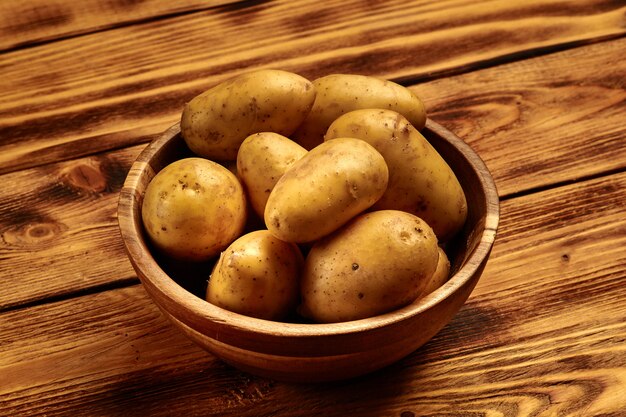 Pommes de terre nouvelles crues dans un plat en bois sur fond de bois