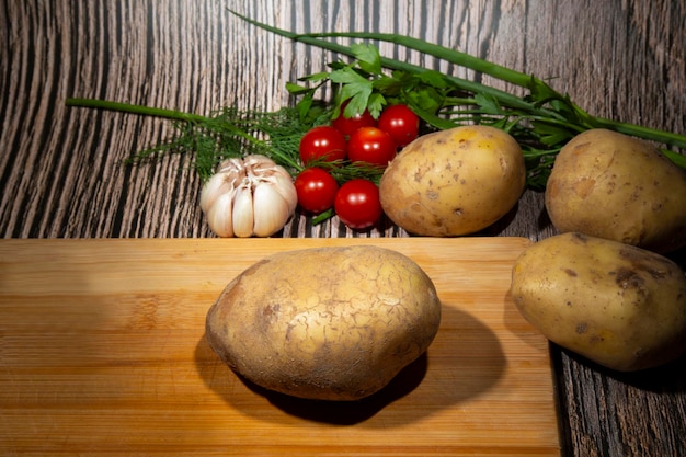 Pommes de terre nouvelles sur une planche à découper à côté de tomates à l'ail le concept d'une alimentation saine