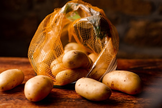 Pommes de terre en paquet sur fond de bois Achat ou vente de pommes de terre en filet de polyéthylène Fond sombre