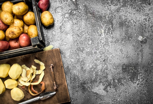 Photo pommes de terre pelées sur planche de bois sur table rustique.