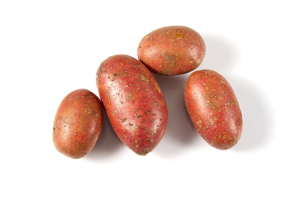 Pommes de terre rouges fraîchement déterrées qui reposent sur le fond blanc