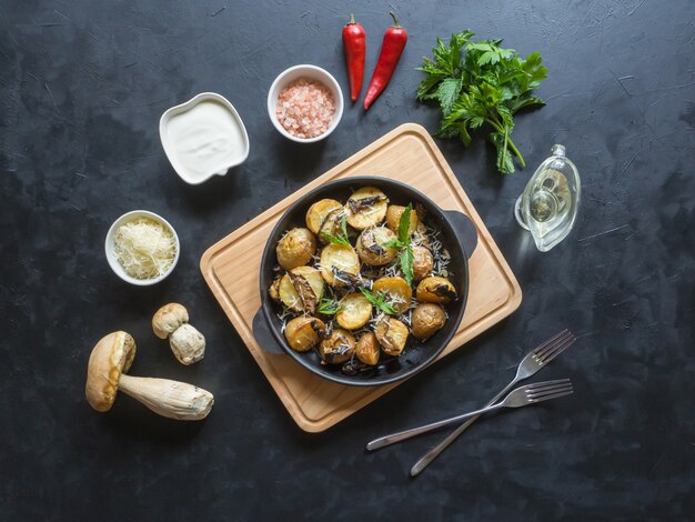 Pommes de terre rustiques aux champignons sur un tableau noir. Vue de dessus.