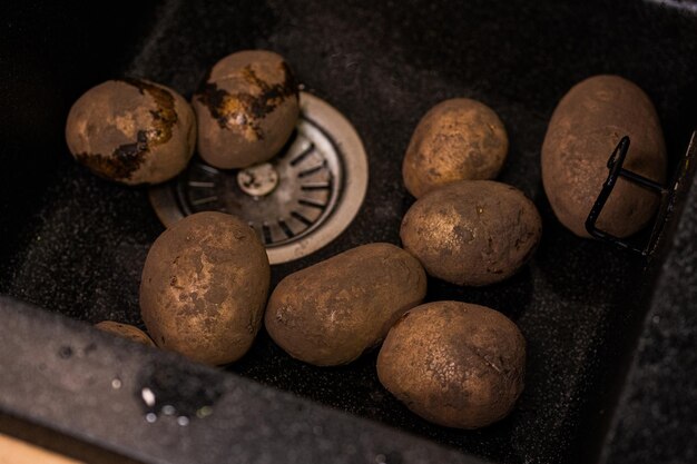 Photo pommes de terre sales dans l'évier préparant les légumes pour le lavage à la maison