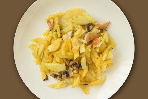 Photo pommes de terre sautées aux champignons et poulet sur une assiette blanche. repas quotidien traditionnel de la cuisine russe moderne