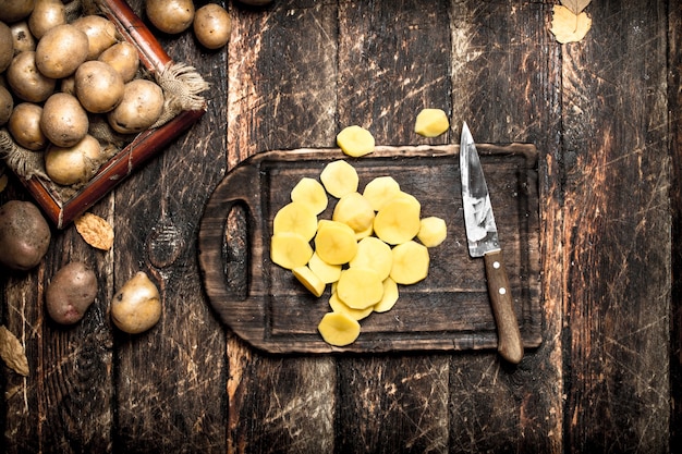 Les pommes de terre en tranches sur une vieille planche de bois