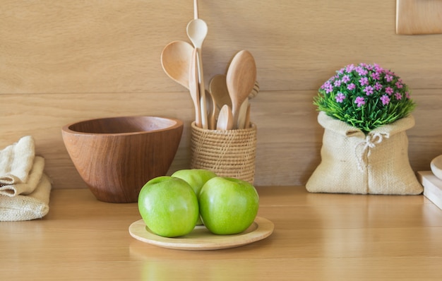 Pommes vertes et assiettes en bois dans la cuisine.