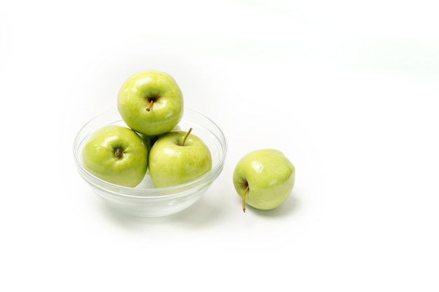 Pommes vertes dans une assiette transparente sur fond blanc. Alimentation saine