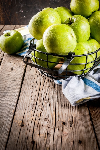 Pommes vertes de ferme biologique crue fraîche dans un panier en métal noir, vieux bois rustique, fond