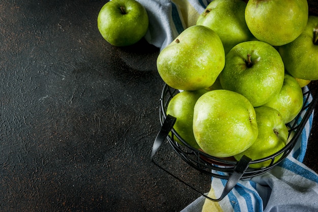 Pommes vertes de ferme biologiques crues fraîches dans un panier en métal noir, rouillé foncé, fond