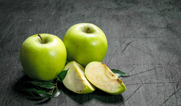 Pommes vertes avec des feuilles sur table rustique.