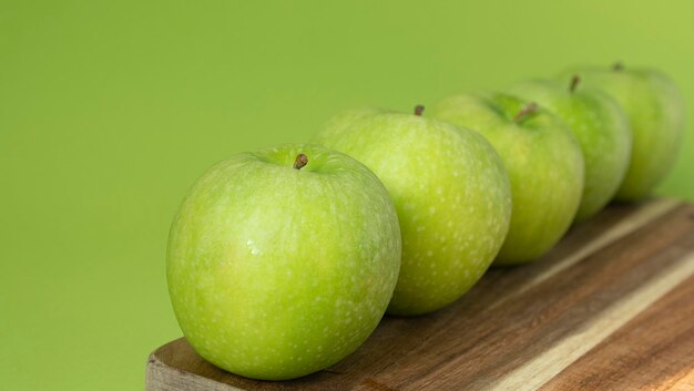 Pommes vertes et fraîches sur fond de bois et de couleur verte