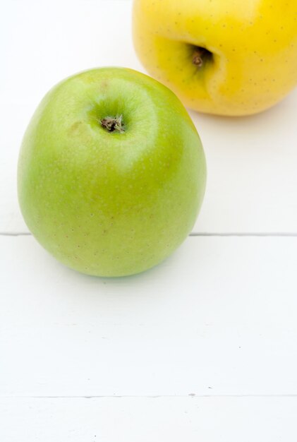 Pommes vertes et jaunes sur un gros plan de fond en bois blanc