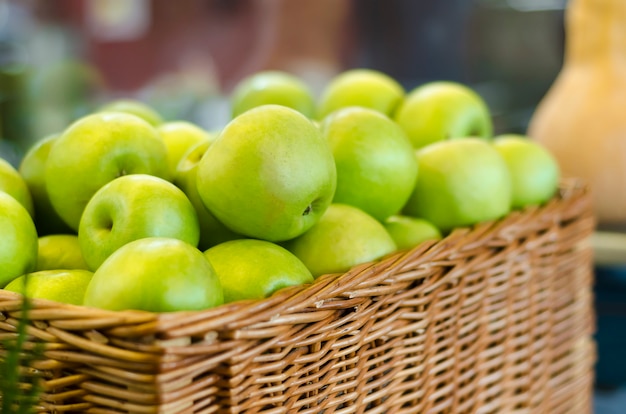 Pommes vertes mûres dans un panier en osier