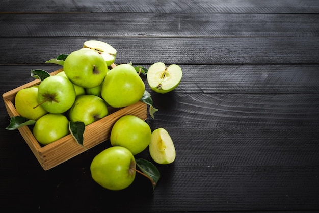 Pommes vertes savoureuses et fraîches dans une boîte en bois sur le fond en bois noir. Vue de dessus. Copier l'espace