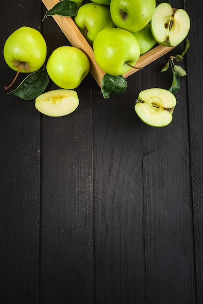 Pommes vertes savoureuses et fraîches dans une boîte en bois sur le fond en bois noir. Vue de dessus. Copier l'espace