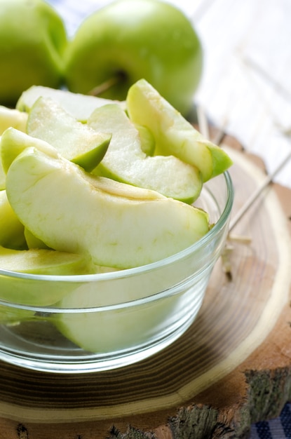 Pommes vertes tranchées mûres sur fond en bois