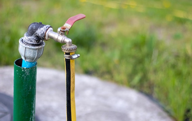 Pompe à eau de plomberie d'un puits Un robinet d'eau extérieur avec un tuyau d'arrosage jaune attaché