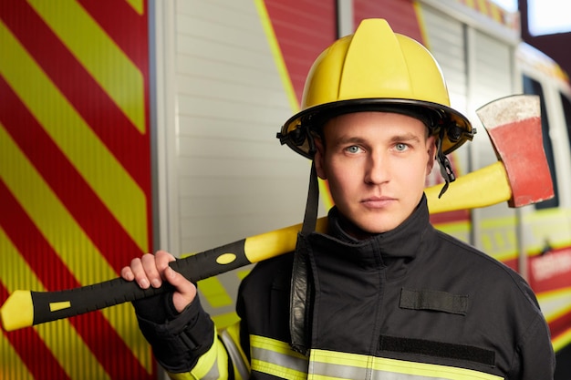 Pompier entièrement équipé d'un casque et d'une hache sur fond de camion de pompiers