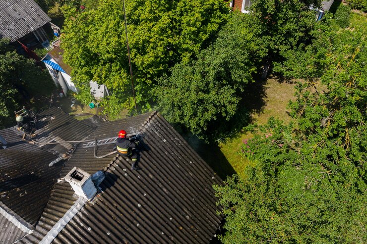 Photo un pompier est assis sur le toit d'une maison en feu