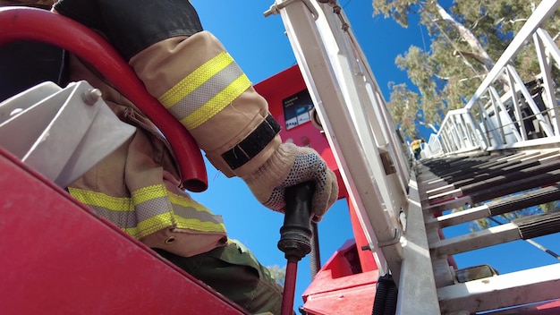 Pompier faisant du sauvetage d'arbres au sommet d'un camion échelle.