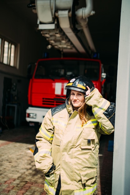 Pompier féminin en uniforme de protection debout près d'un camion de pompiers rouge