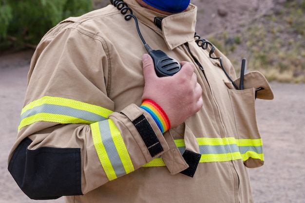 Pompier parlant à portée de main, avec bracelet LGBT.