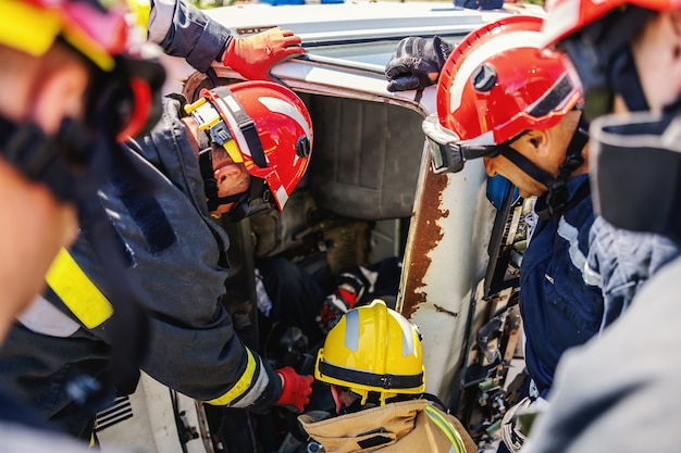 Photo les pompiers essayant de libérer l'homme empilé dans une voiture