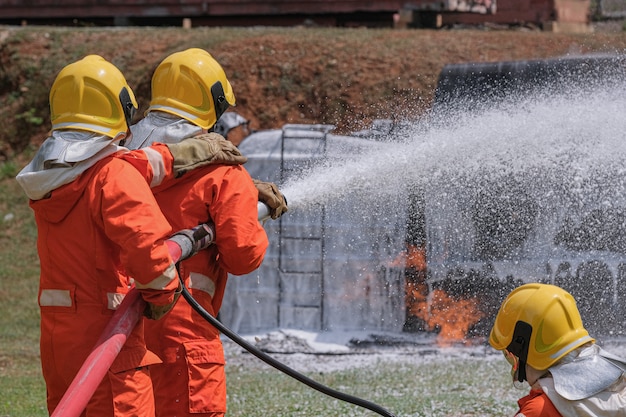 Les pompiers éteignent le feu avec une mousse chimique provenant de la pompe à incendie par un long tuyau.