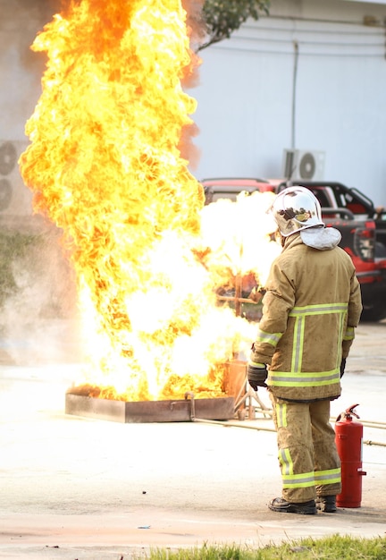 Photo pompiers utilisant un extincteur de type brouillard d'eau twirl pour combattre avec la flamme du feu de l'huile pour contrôler le feu et ne pas se propager concept de pompier et de sécurité industrielle