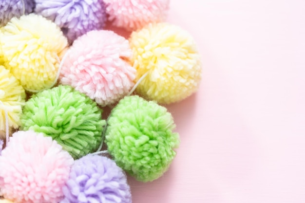 Pompons de couleur pastel sur fond rose.